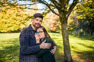 Outdoor portrait of a millennial aged couple embracing.