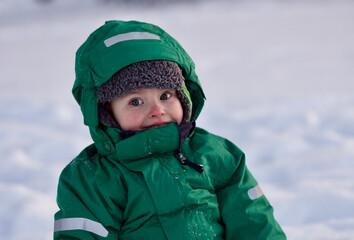 Portrait of smiling little boy playing in snow on cold winter day