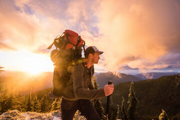 Side view of man backpacking on mountain ridge with scenic view.