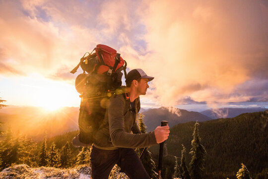 Side view of man backpacking on mountain ridge with scenic view.