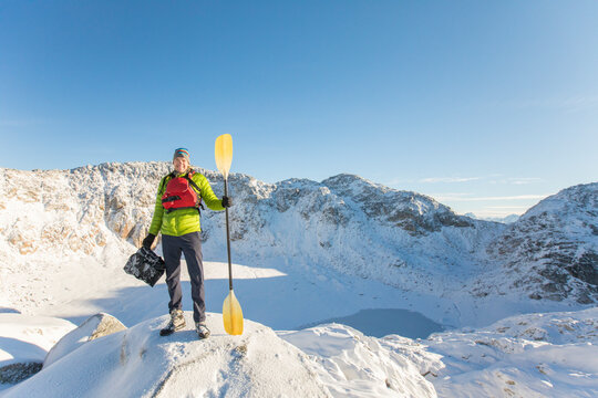 Portrait of paddler wearing life jacket standing above frozen lake