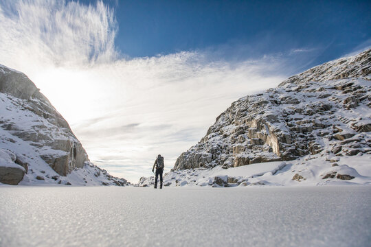 low angle of backpacker exploring snow-covered mountain landscape.
