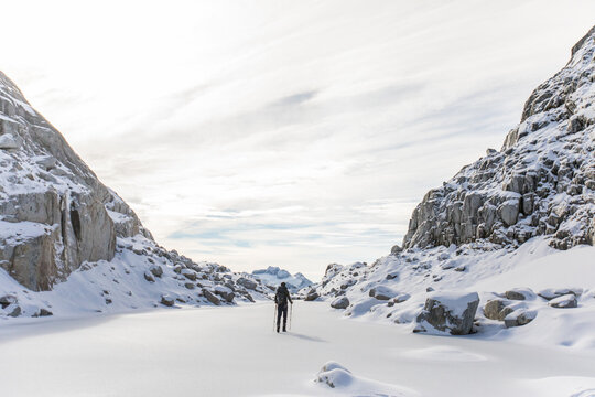 High angle of backpacker exploring snow-covered mountain landscape.