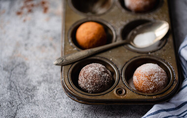 Close up of donut holes covered in sugar in a baking tin.