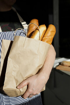 A man holding a bag of baguettes
