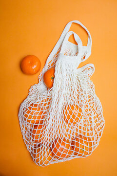 tangerines in a string bag on an orange background