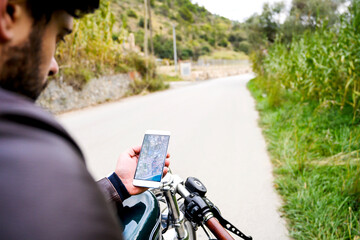Man holding smartphone with road map, sitting on vintage motorbike
