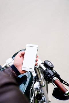 Man holding smartphone while sitting on vintage motorbike