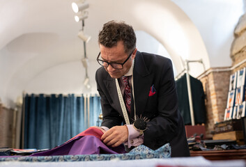 Serious male tailor selecting material