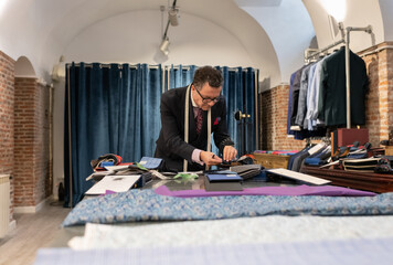 Senior dressmaker choosing fabric from catalog