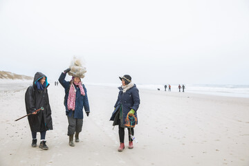 Three Friends Carrying Trash On Beach Along North Sea in Denmark