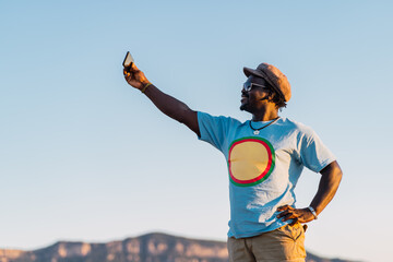 smiling african american man with mobile phone taking a picture