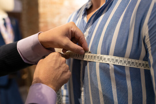 Cropped tailor measuring chest of client