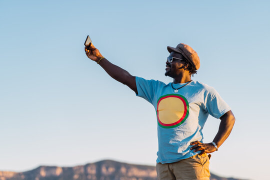 smiling african american man with mobile phone taking a picture