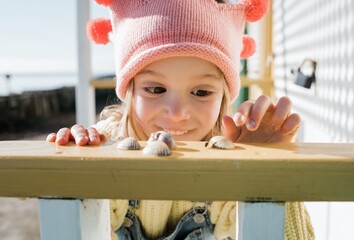 young girl happily choosing a shell from her collection at the beach