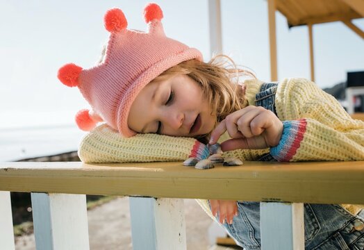 child playfully choosing shells using her imagination at the beach