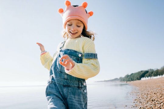 girl playfully running on the beach playing dress up in the sun