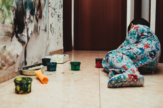 Child lying on the floor playing with acrylic paint