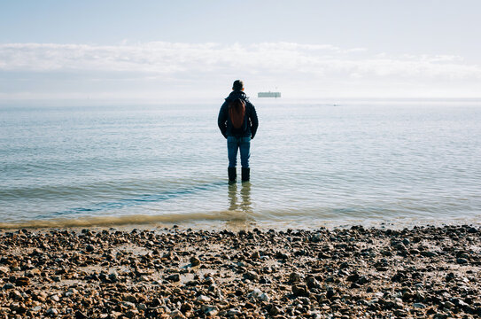 man stood in the ocean thinking, contemplating and dreaming in the sun