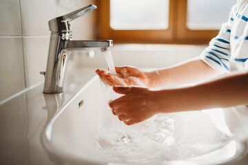 Close up of young hands being washed with soap