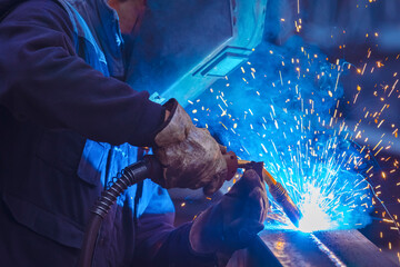 Man with protective face and eye shield welding industrial steel beam