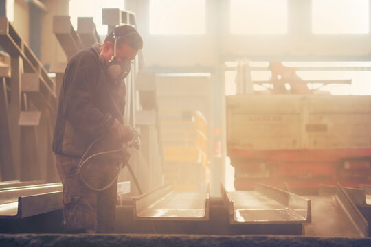 Man painting industrial and lacquering steel with compressor machine