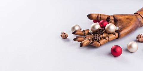 Wooden hand with christmas red and golden ornaments on gray