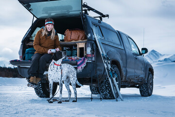 Happy woman with dog in off-road vehicle during winter