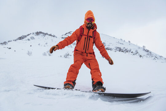 Smiling man snowboarding on snowcapped mountain in vacation