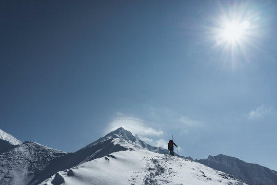 Low angle view of man splitboarding against sky during sunny day