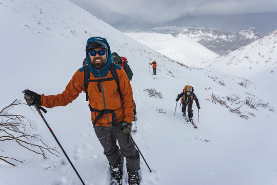 People with ski poles splitboarding on snowcapped mountain during vacation