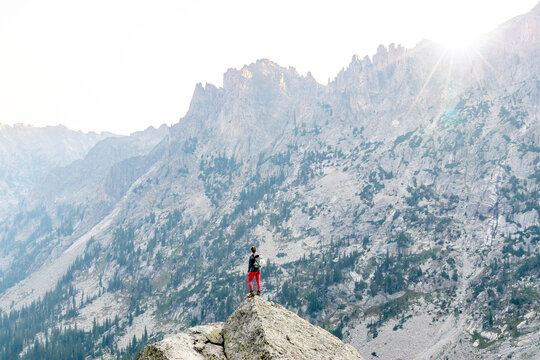 Rear view of woman standing on rock against mountain while hiking during vacation