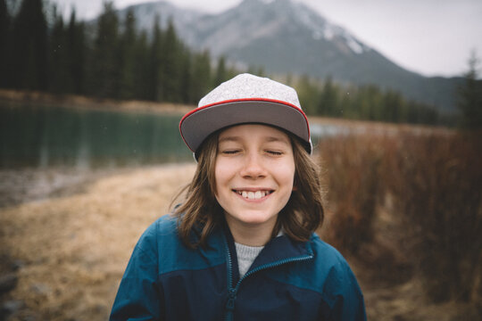 Boy Grins with Eyes Closed By The Bow River in Banff