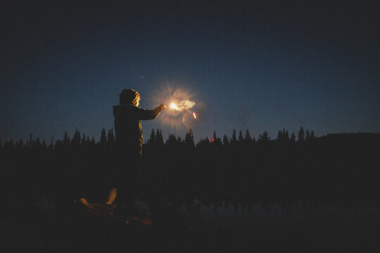 Tween  Boy's Face Is illuminated by a glowing sparkler at Twilight