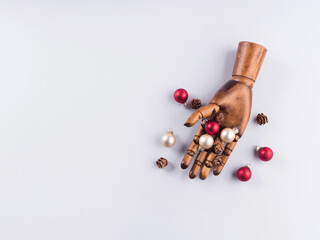 Wooden hand with christmas red and golden ornaments on gray