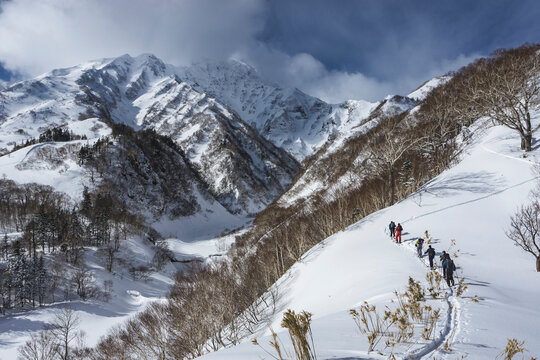 People splitboarding on snowcapped mountain against sky during vacation