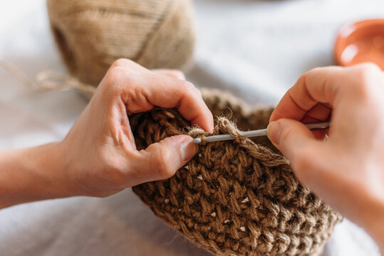 Close-up of woman's hands knitting from jute