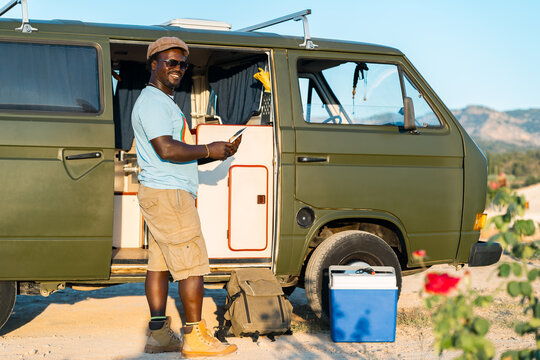 black man with glasses, and mobile phone in camper van