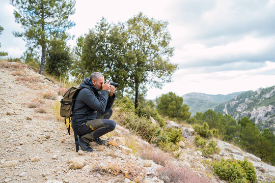 Caucasian man with backpack and camera in the mountains