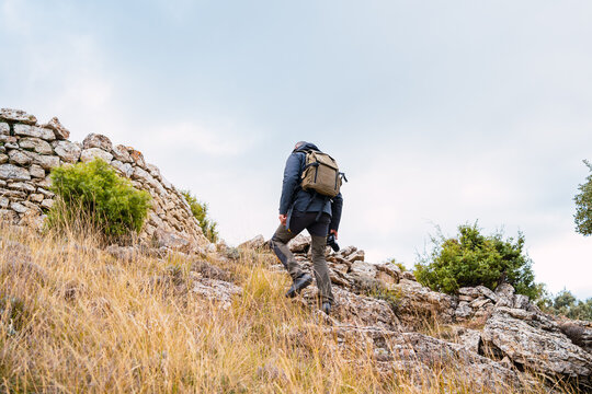 Caucasian man with backpack and camera walking through the mountain