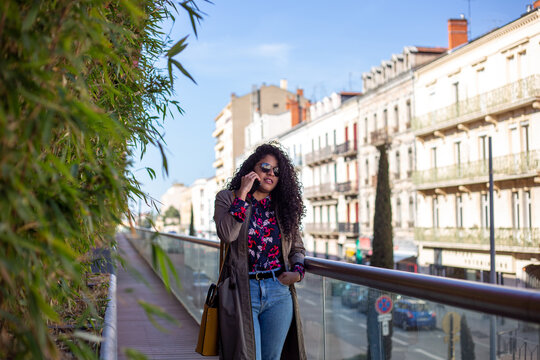 happy african american young woman talking with cellphone in city