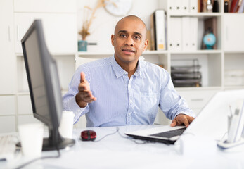 Hispanic confident man working in modern office full of light