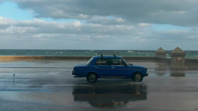 russian car driving on the malecon with ocean waves, Havana, Cuba