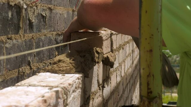 CLOSE UP Bricklayer Places Brick Onto Wet Mortar At House Construction
