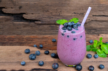 Blueberry smoothie purple colorful fruit juice milkshake blend beverage healthy high protein the taste yummy In glass drink episode morning on wooden background.