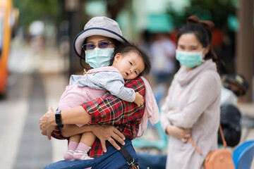 Fototapeta premium woman with medical mask to protect coronavirus(covid-19) while holding baby in city