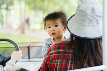 baby with woman sitting in golf cart to travel in zoo