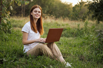 woman outdoors sitting on the grass with laptop summer vacation communication