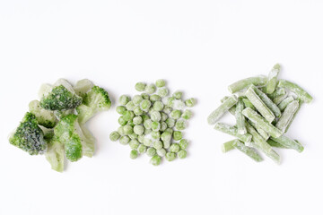Frozen broccoli, green peas and asparagus on white background close up, top view.