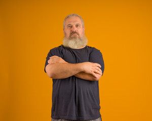 serious bearded man crossed his arms over his chest on a yellow background